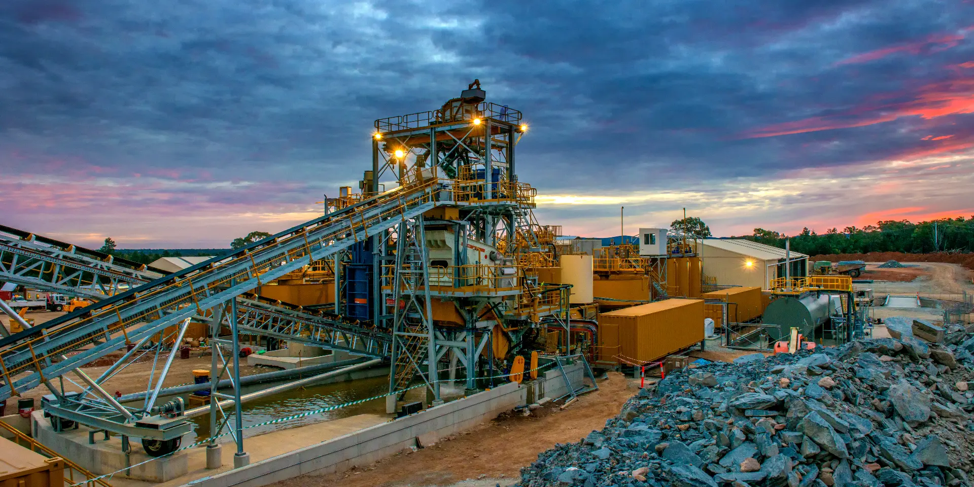 Mineral processing plant and conveyor systems at a mine site at dusk.