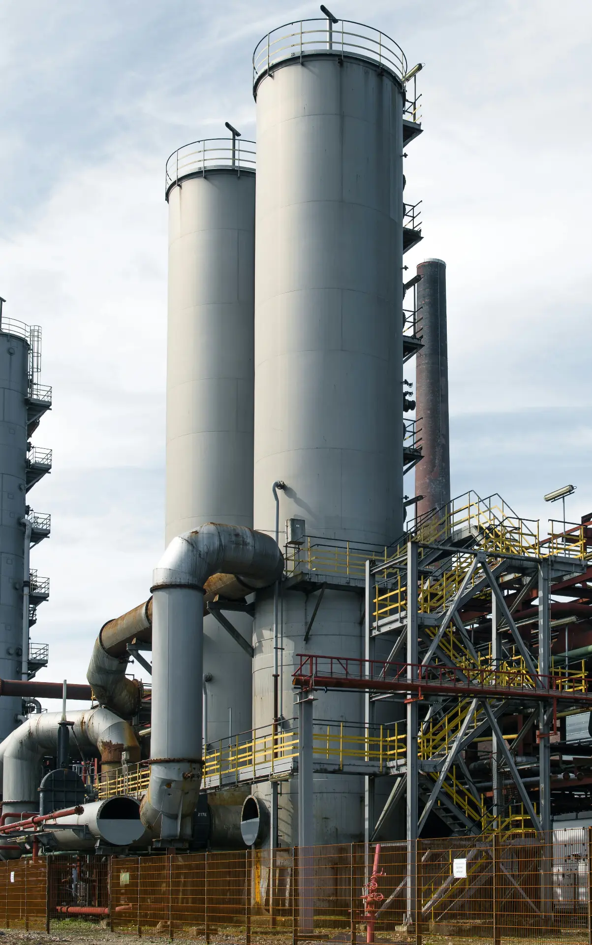 Process columns, pipework and access stairways at an operating industrial facility.