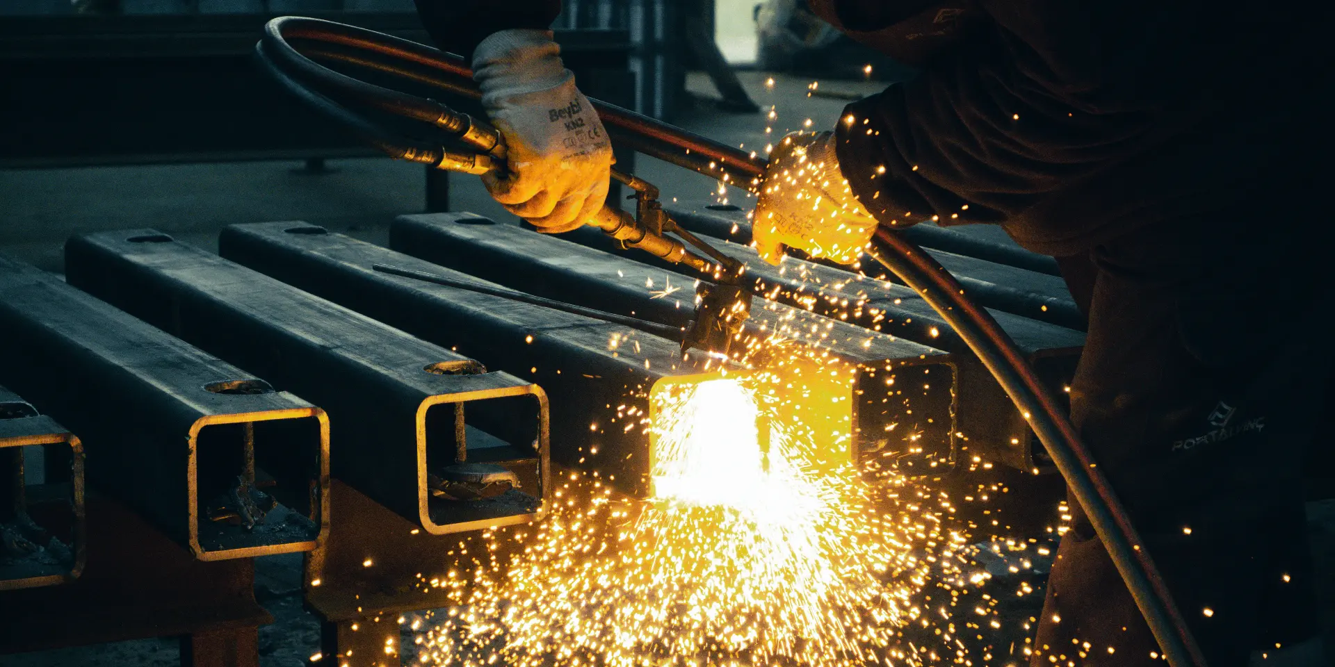 Oxy-fuel cutting of structural steel sections in a fabrication shop.