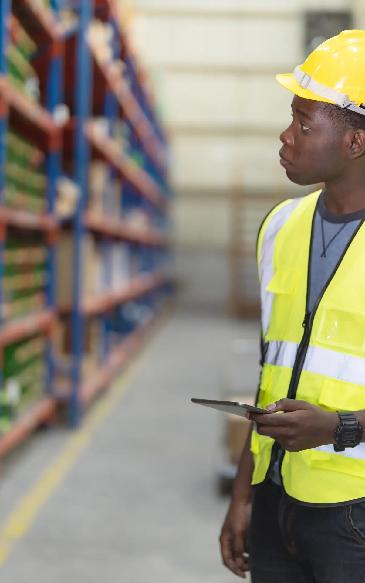 Supply-chain specialist checking warehouse stock against a tablet in a high-bay store.