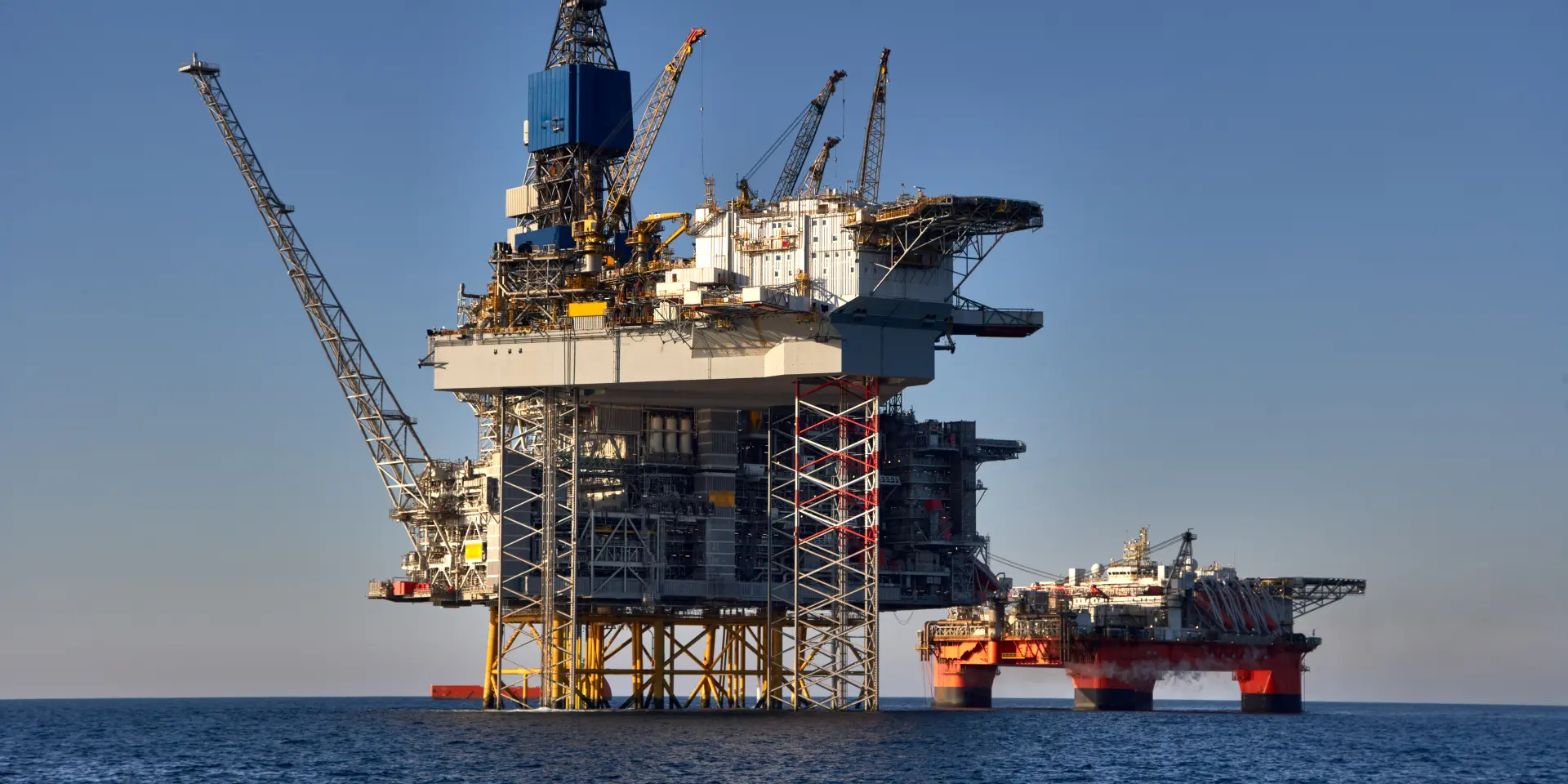 Fixed offshore production platform and semi-submersible unit at sea.